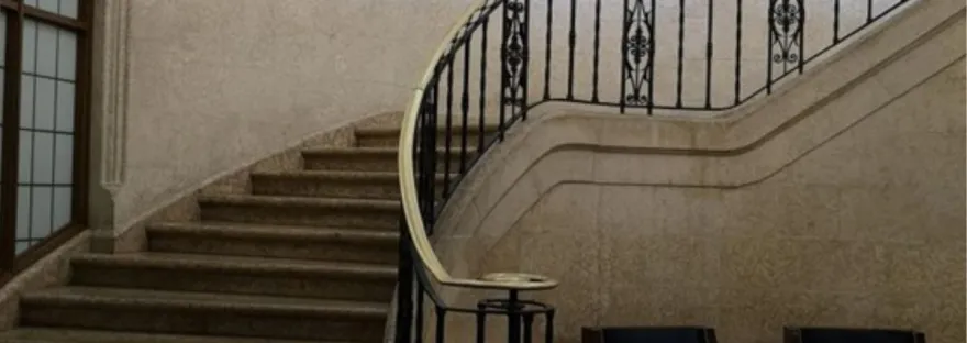 Picture of an old stone stairwell with an ornate bannister